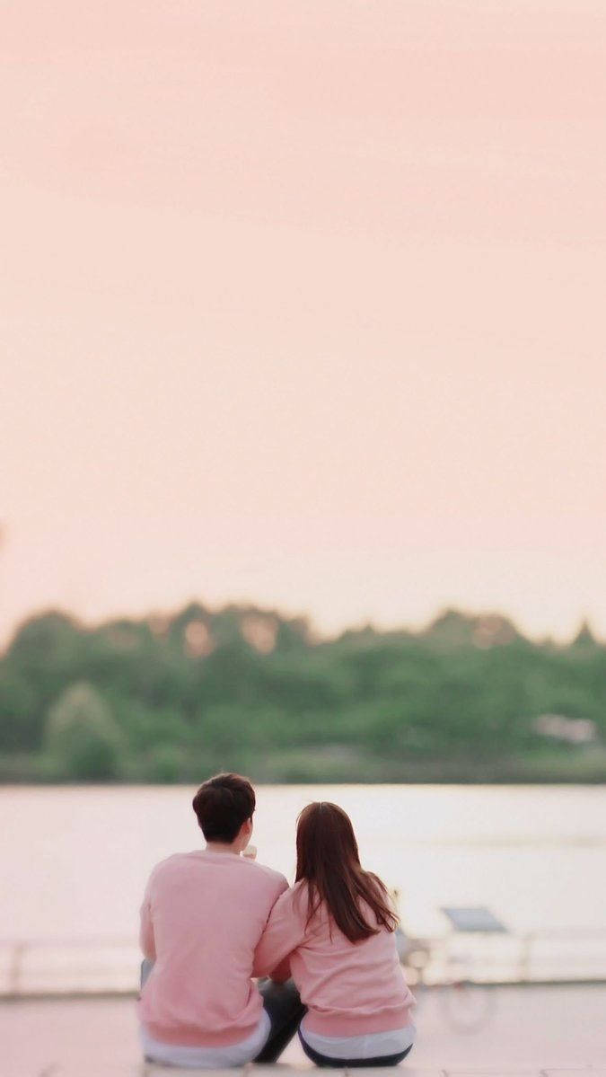 Cute Couple In Pink Shirts Viewing River Background