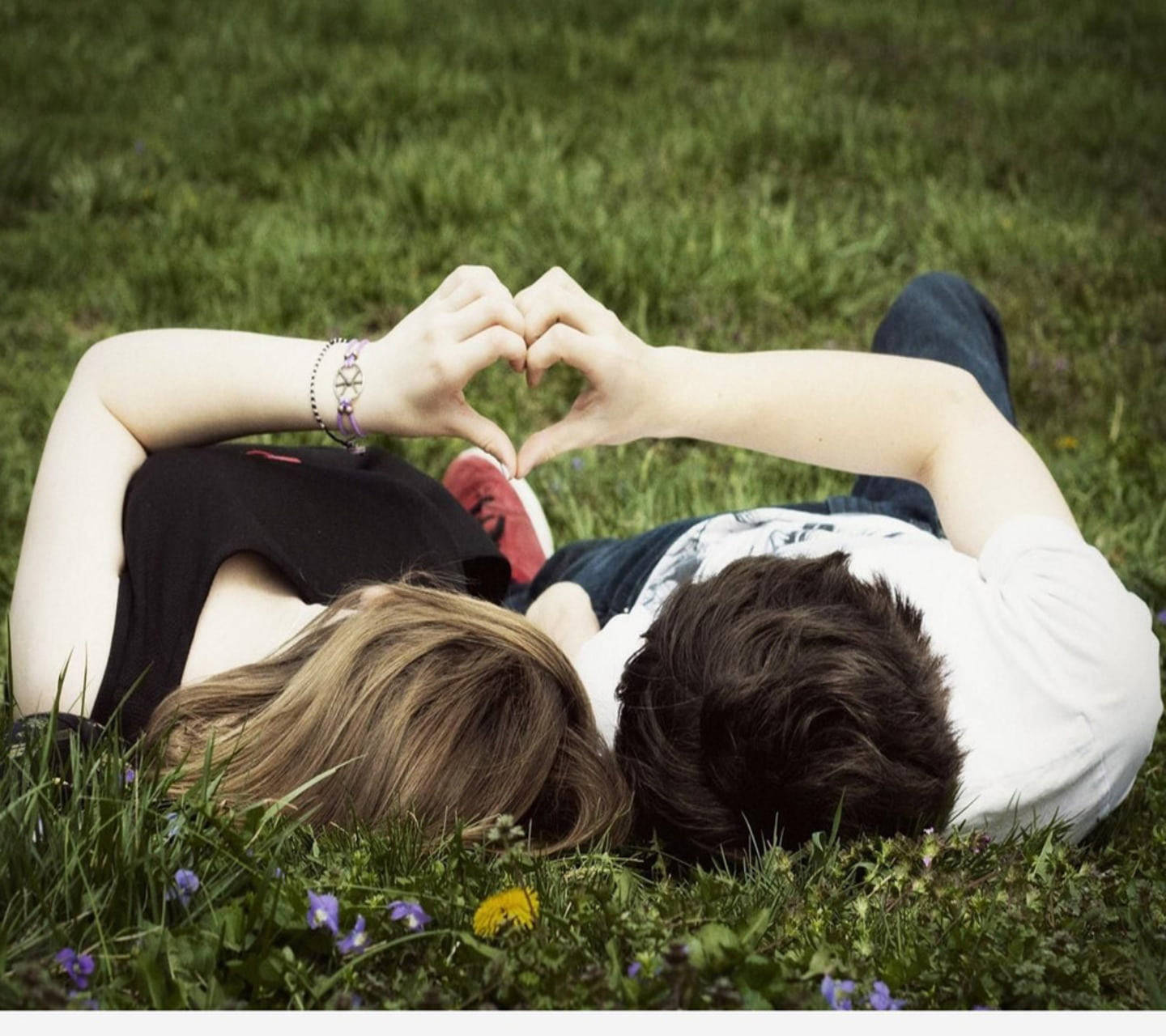 Cute Couple Making Cute Heart On Grass Background