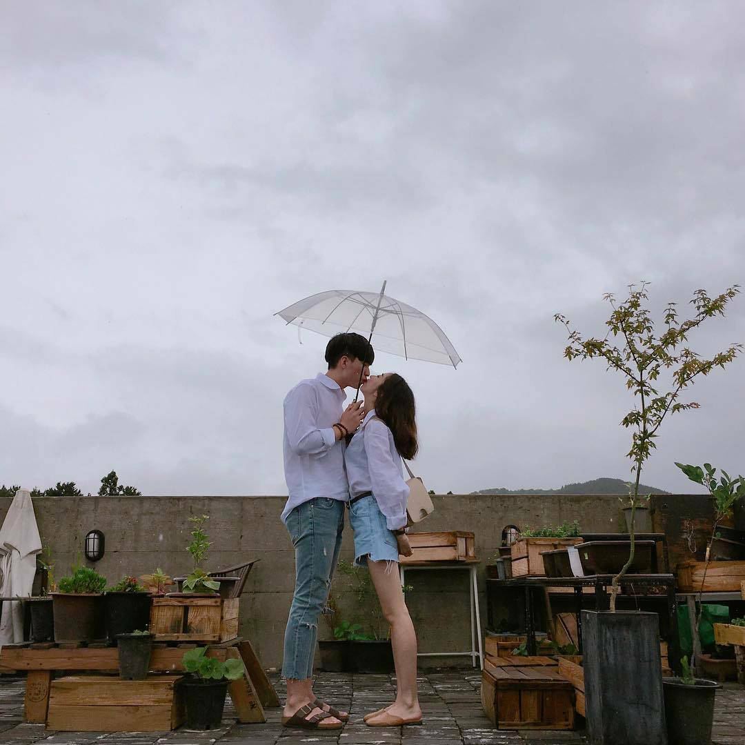 Cute Couple With Umbrella At A Rooftop Cafe Background