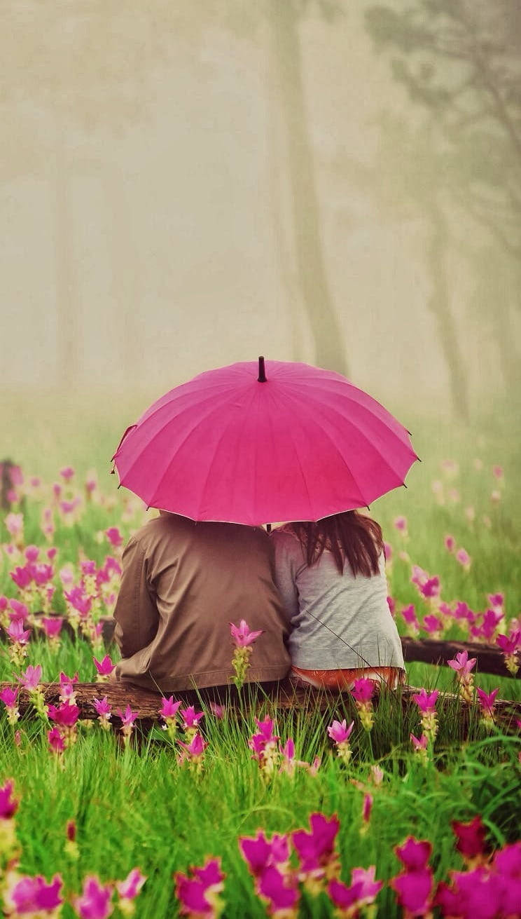 Cute Couple With Umbrella In Flower Garden Background