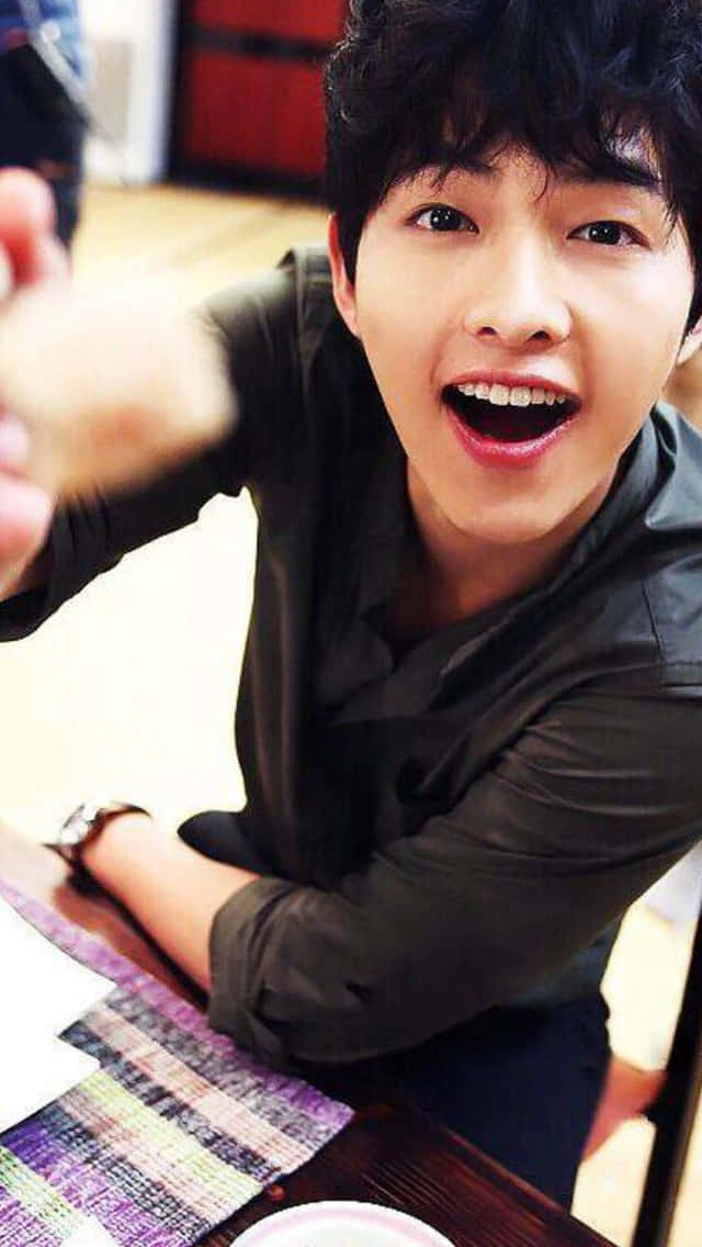 Cute Korean Actor Song Joong Ki Holding A Spoon Background