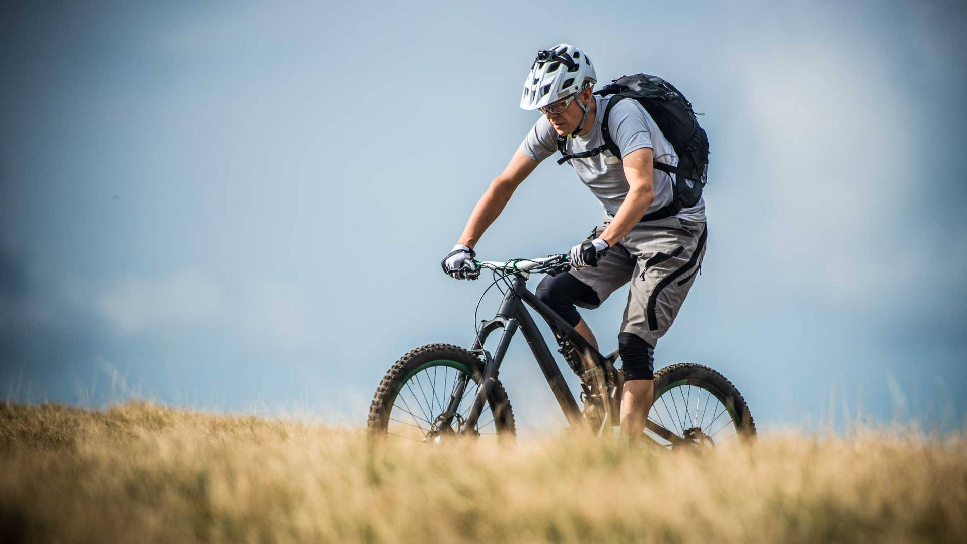 Cyclist Mountain Biking At Mountain Field Background