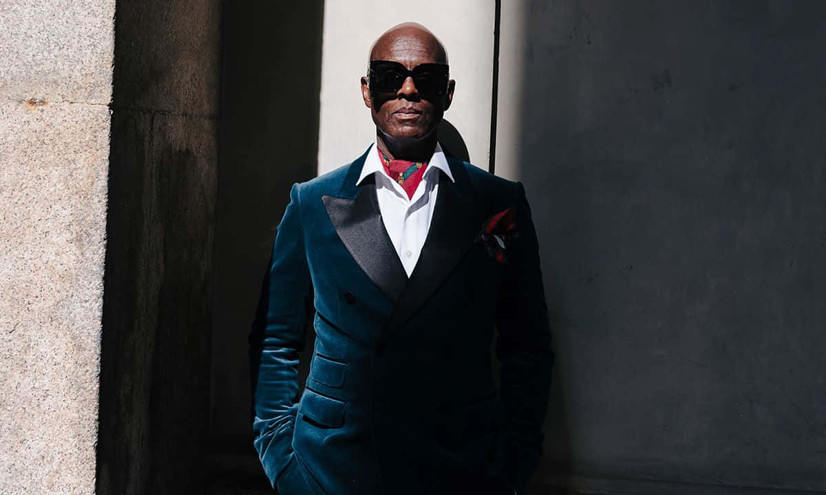 Dapper Dan Leaning Against A Wall Background