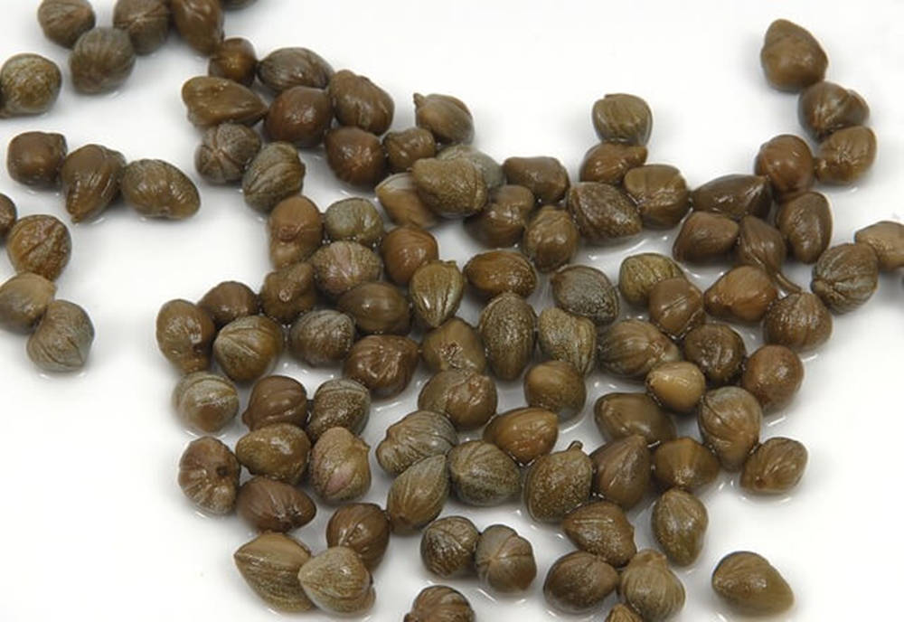 Dark Green Capers On White Surface