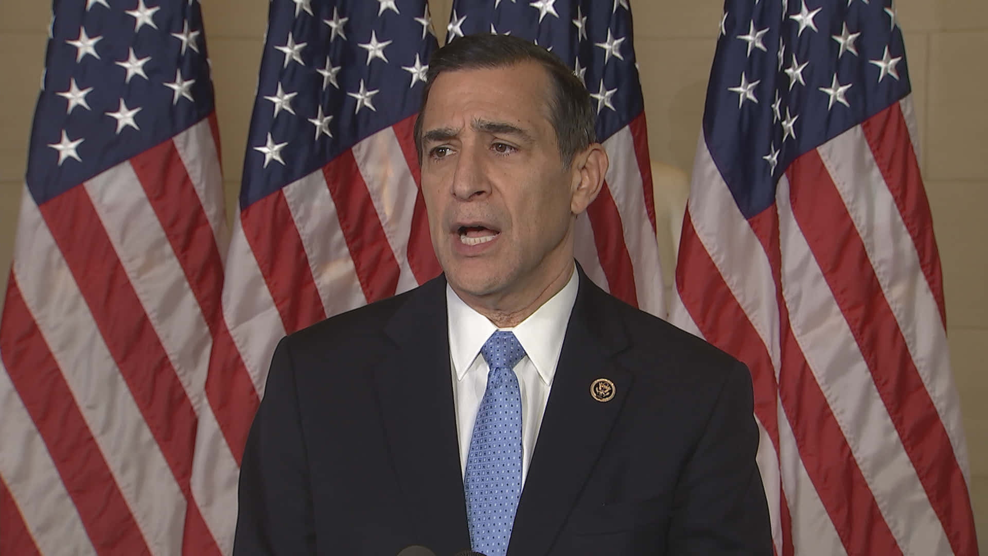 Darrell Issa Standing Proudly In Front Of Four American Flags Background