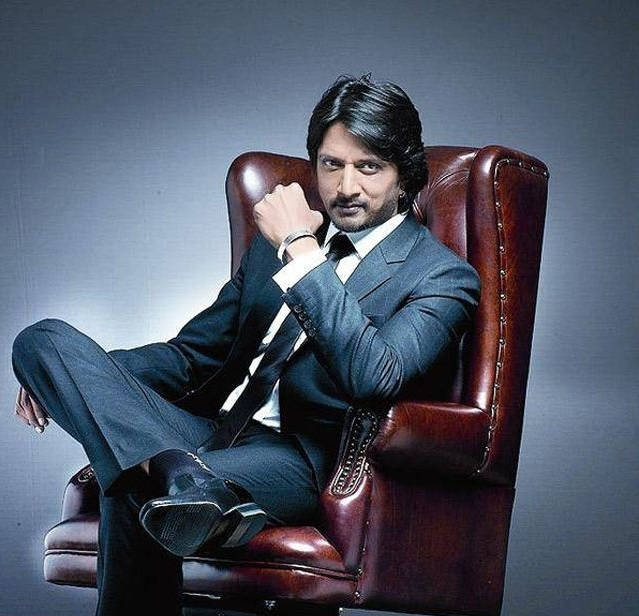 Dashing Sudeep On Maroon Chair Background