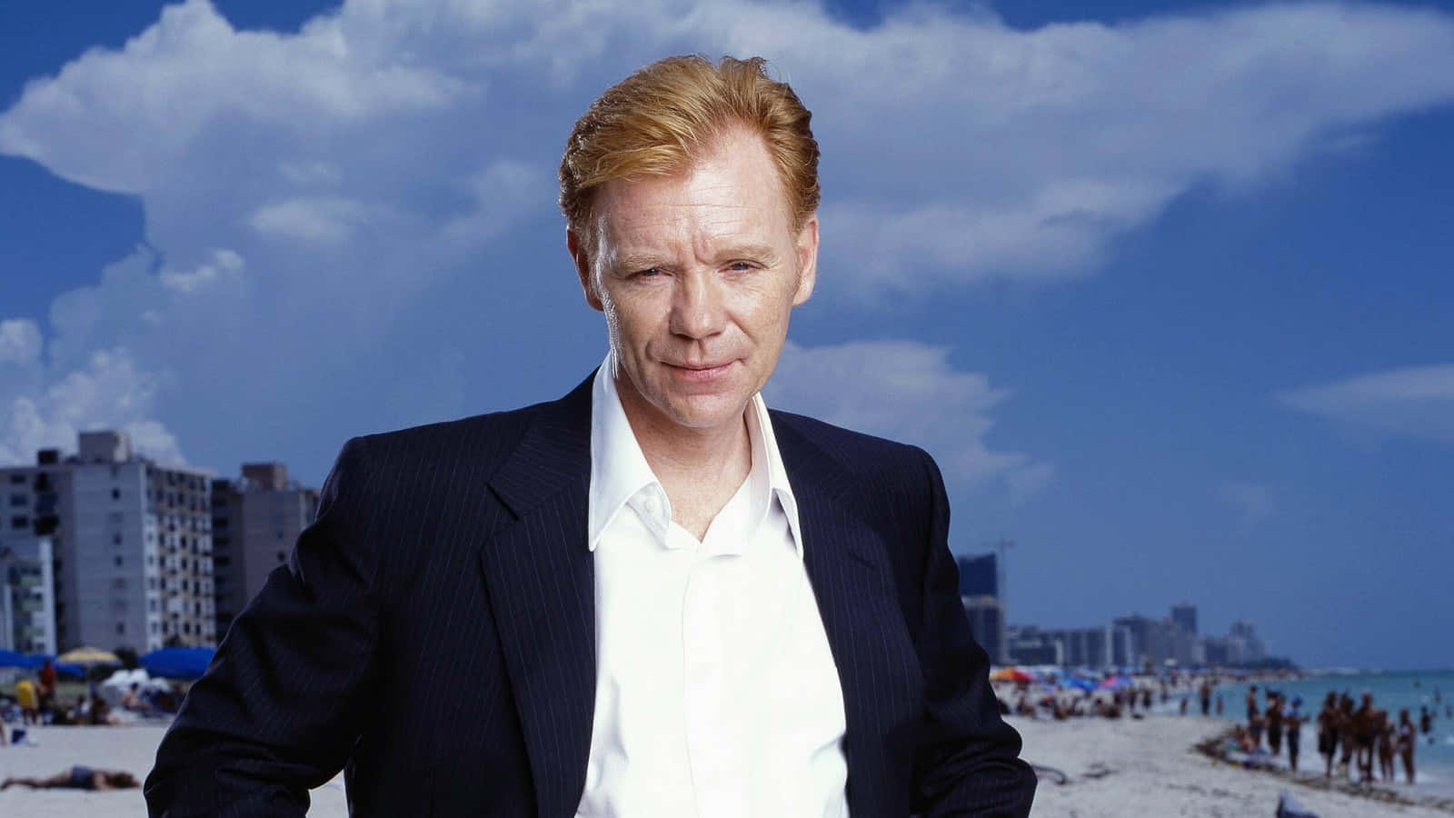 David Caruso Striking A Pose In A Suit Against A City Backdrop Background