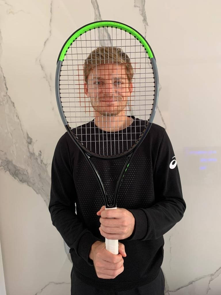 David Goffin Behind Tennis Racket Background