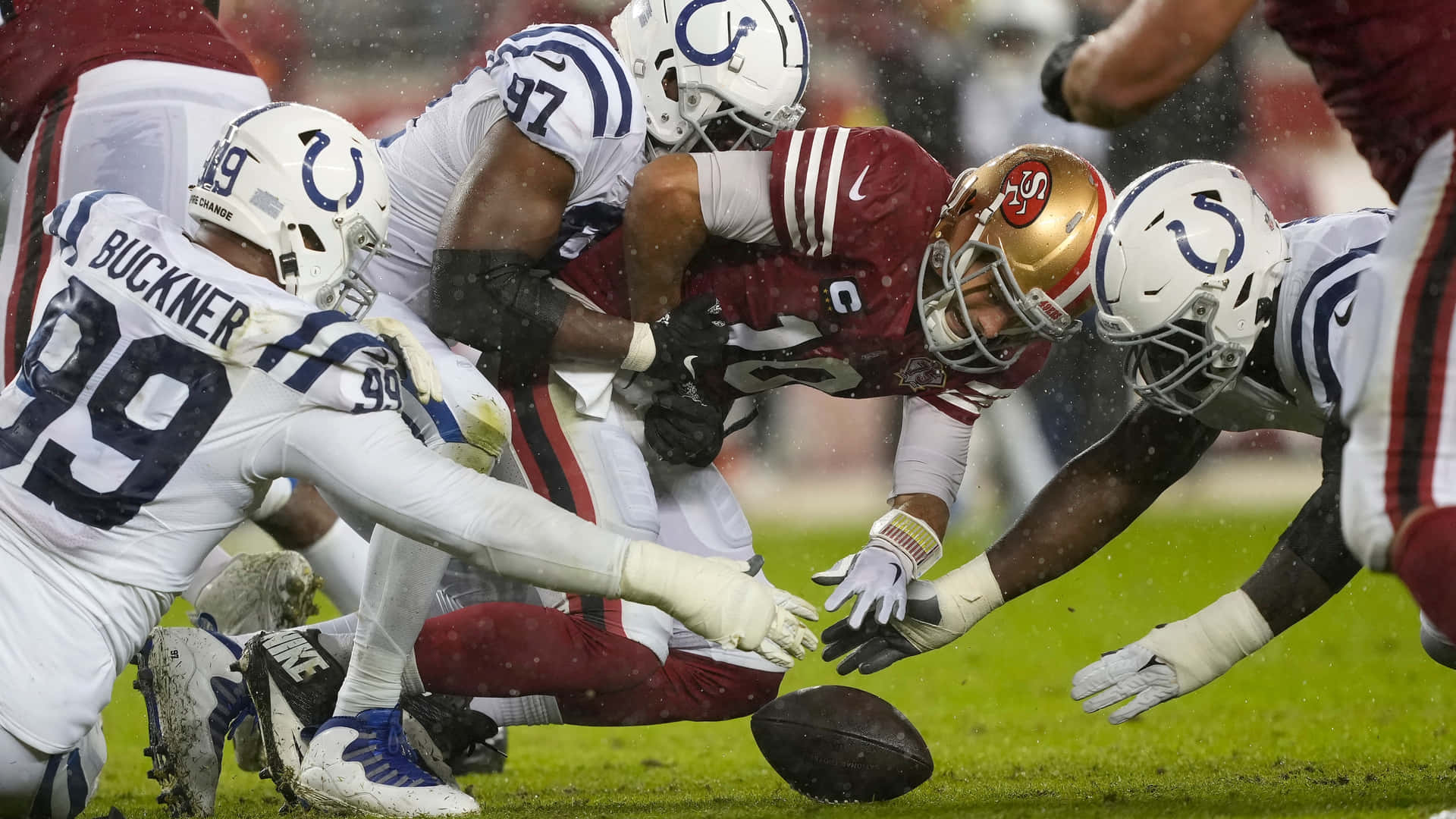 Deforest Buckner Fighting Over Football Background