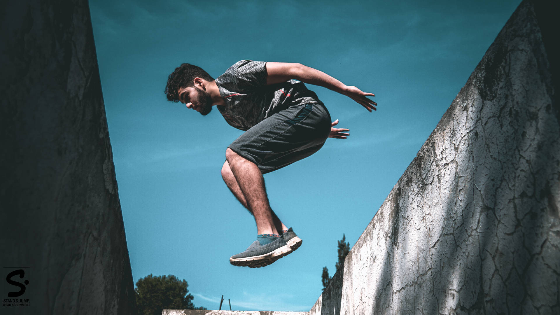 Defying Gravity: A Parkour Enthusiast In Mid-air Background