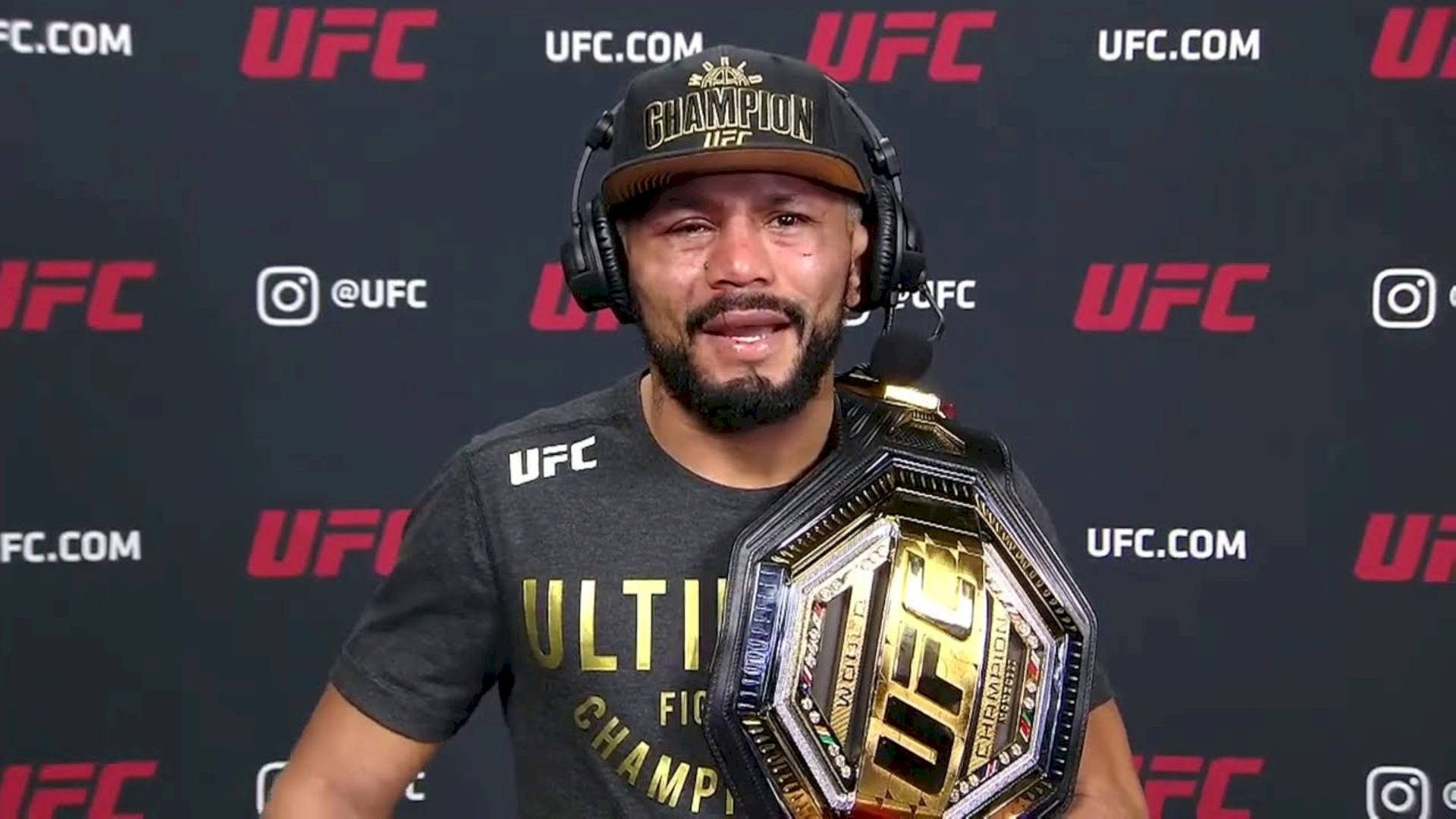 Deiveson Figueiredo Wearing Headset While Holding Championship Belt. Background