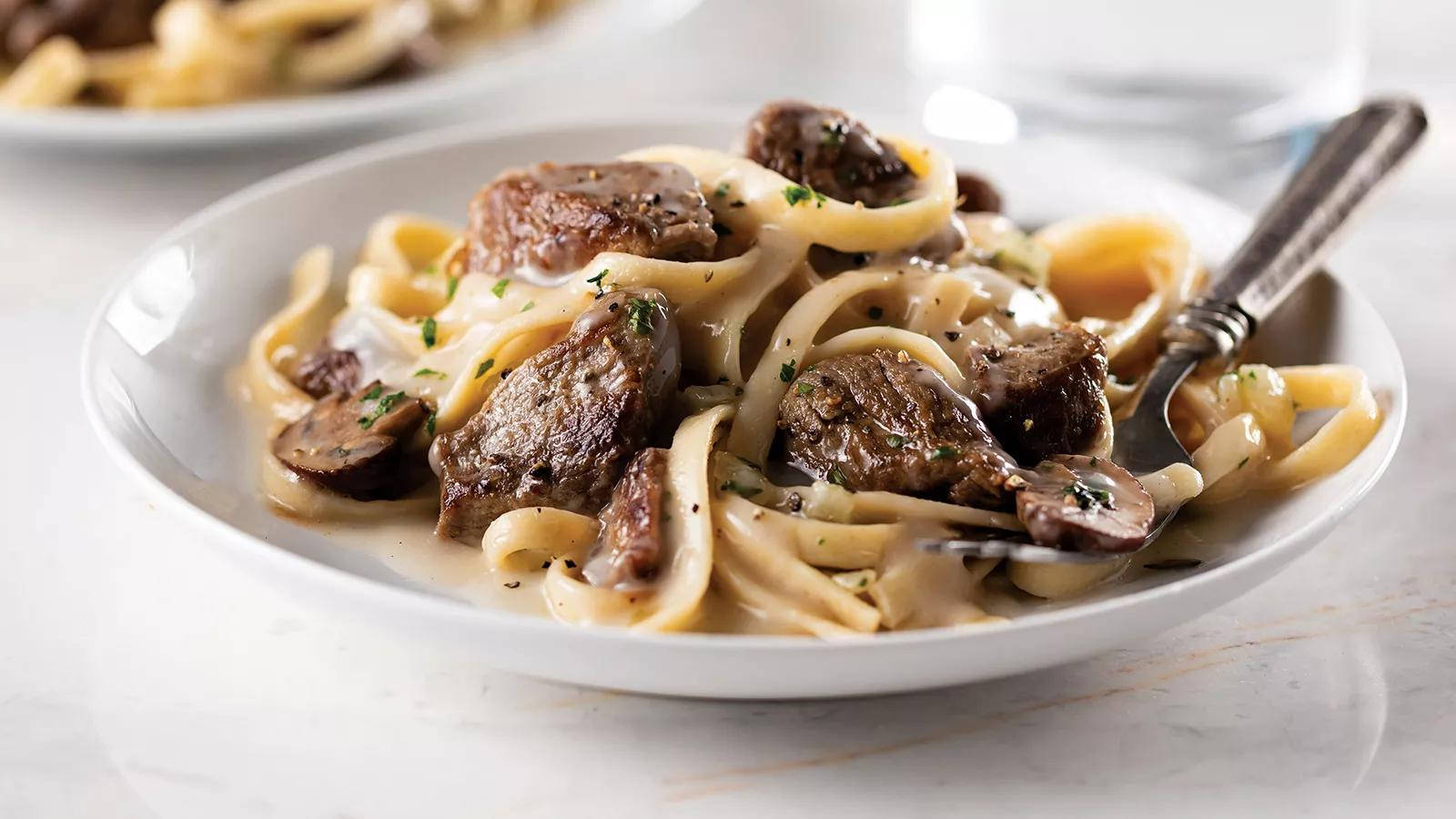 Delectable Beef Stroganoff Served Over Linguine Pasta Background