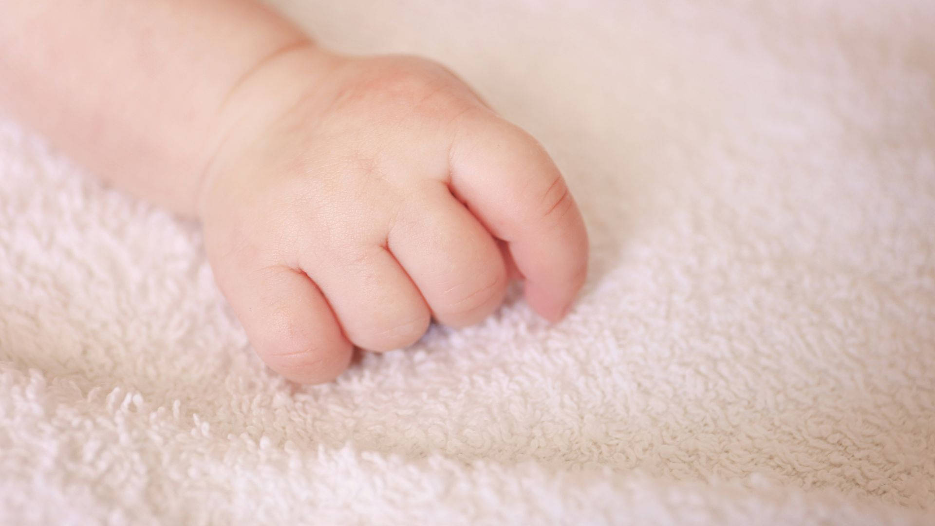 Delicate Baby Hand Resting On Soft Towel Background