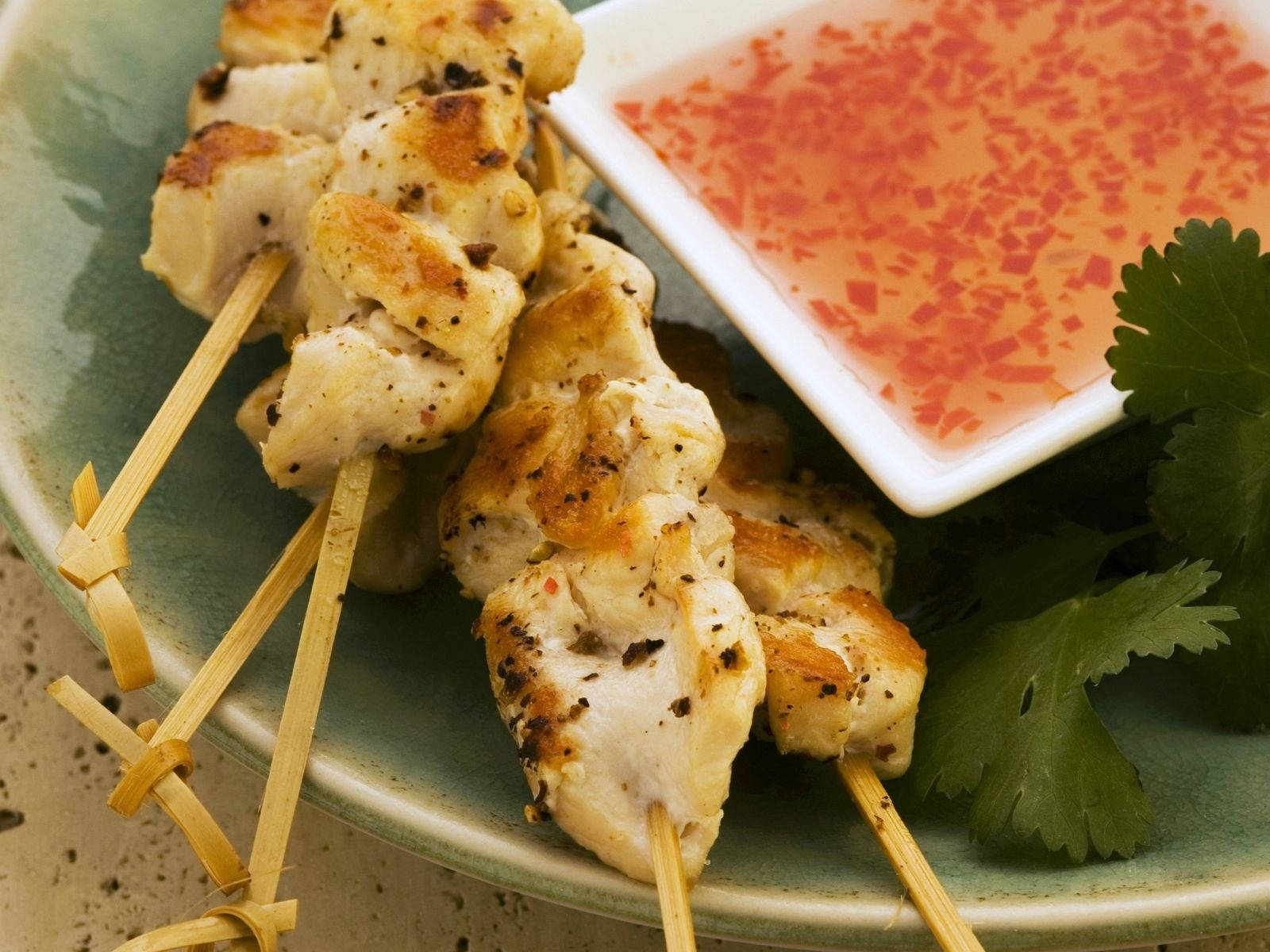 Delicious And Savory Satay Dish Served With Spicy Chili Sauce And Fresh Coriander Leaves Background