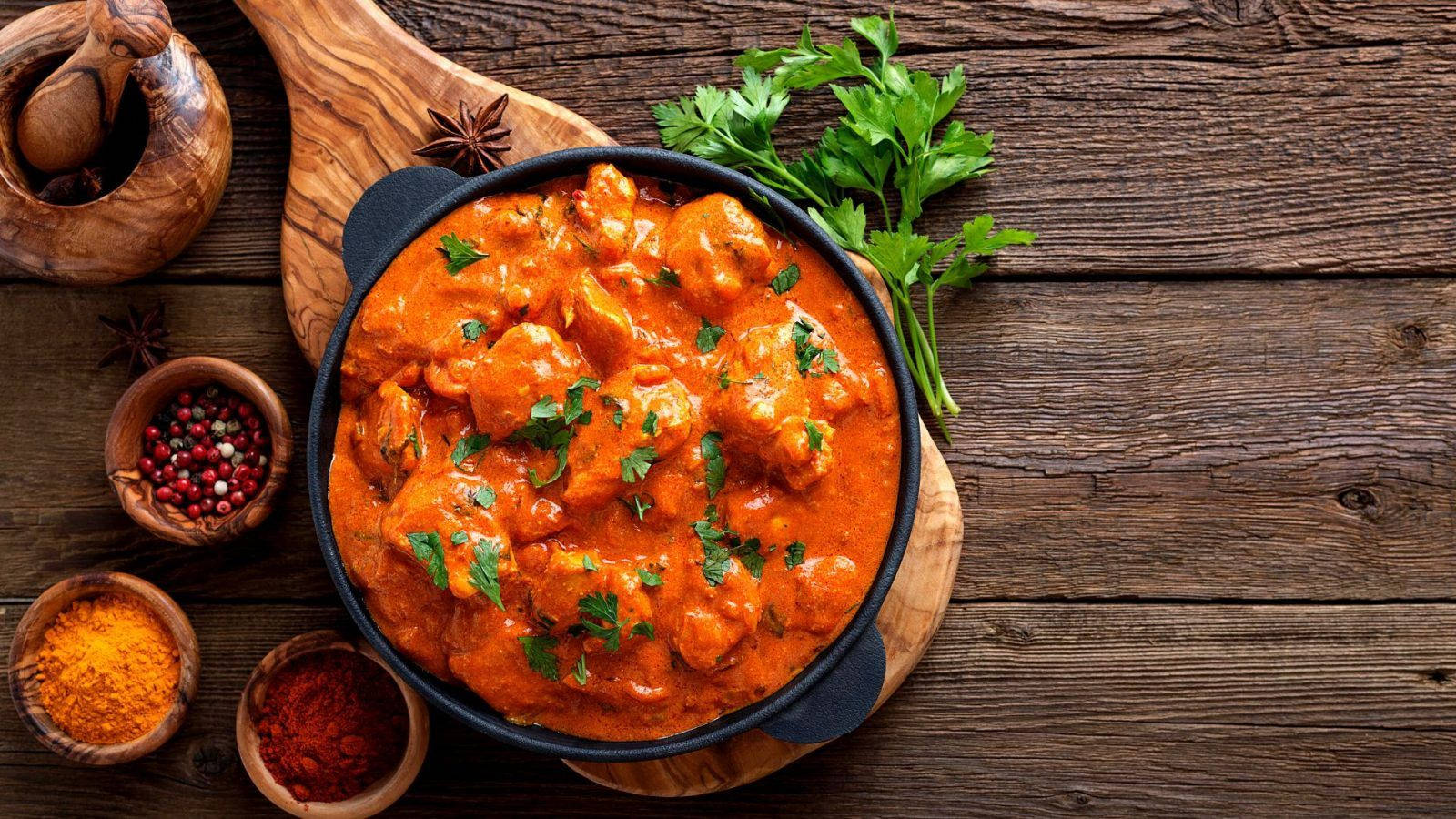 Delicious Butter Chicken Served On A Rustic Wooden Board