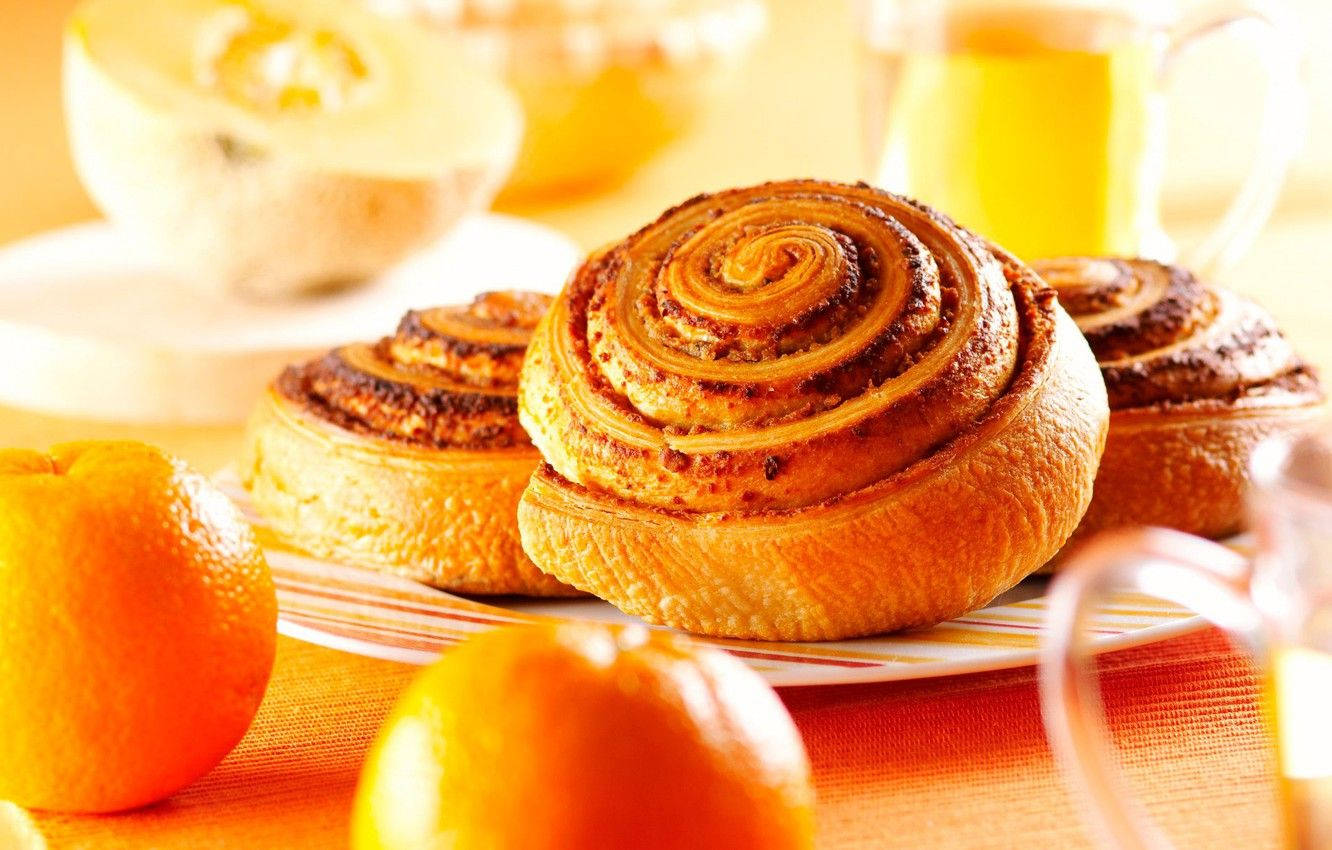 Delicious Cinnamon Rolls Served With Fresh Oranges Background