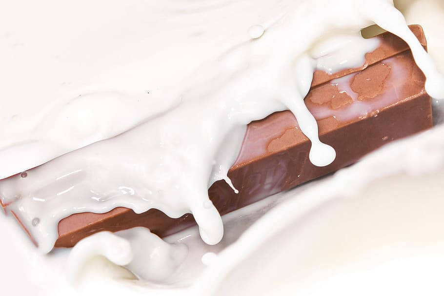 Delicious Kit Kat Chocolate Bars Dipped In Creamy Milk Background