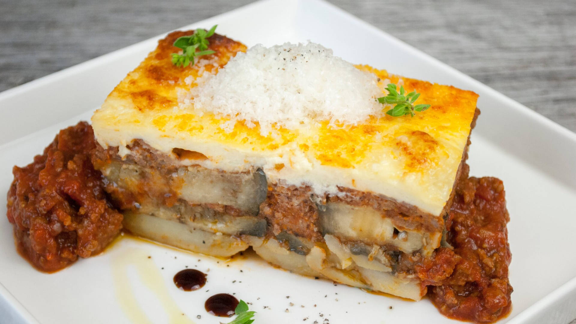 Deliciously Served Sliced Moussaka On A Square Plate Background