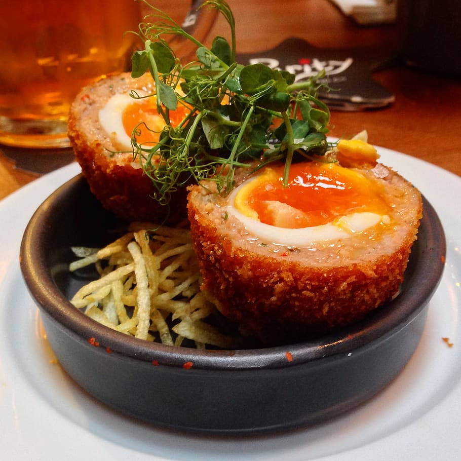 Delightful British Scotch Egg Dish With Pea Tendrils And Fries Background