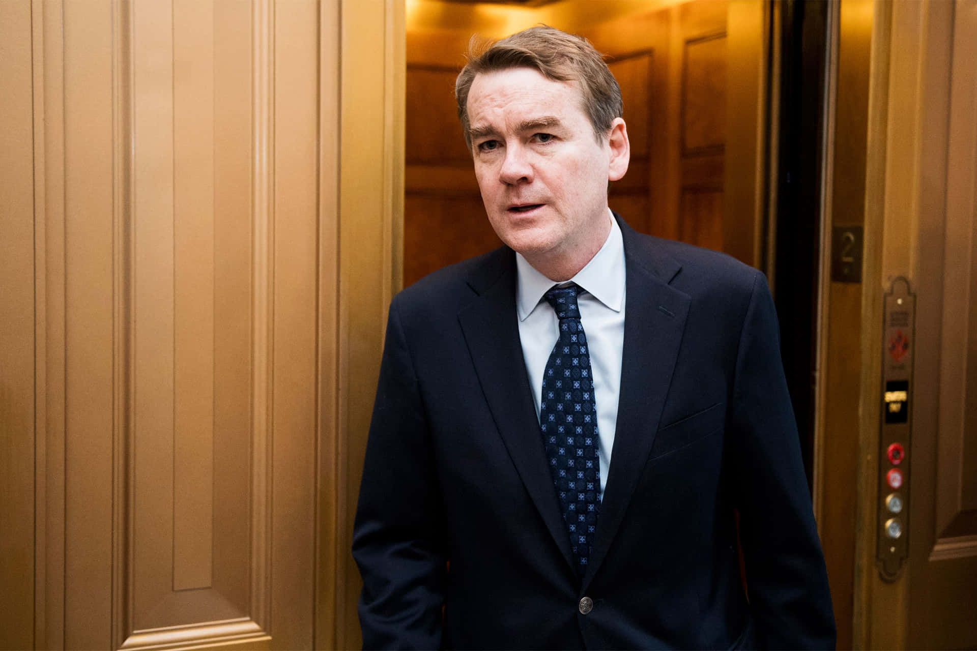 Democratic Presidential Candidate Michael Bennet Leans On Wall Background
