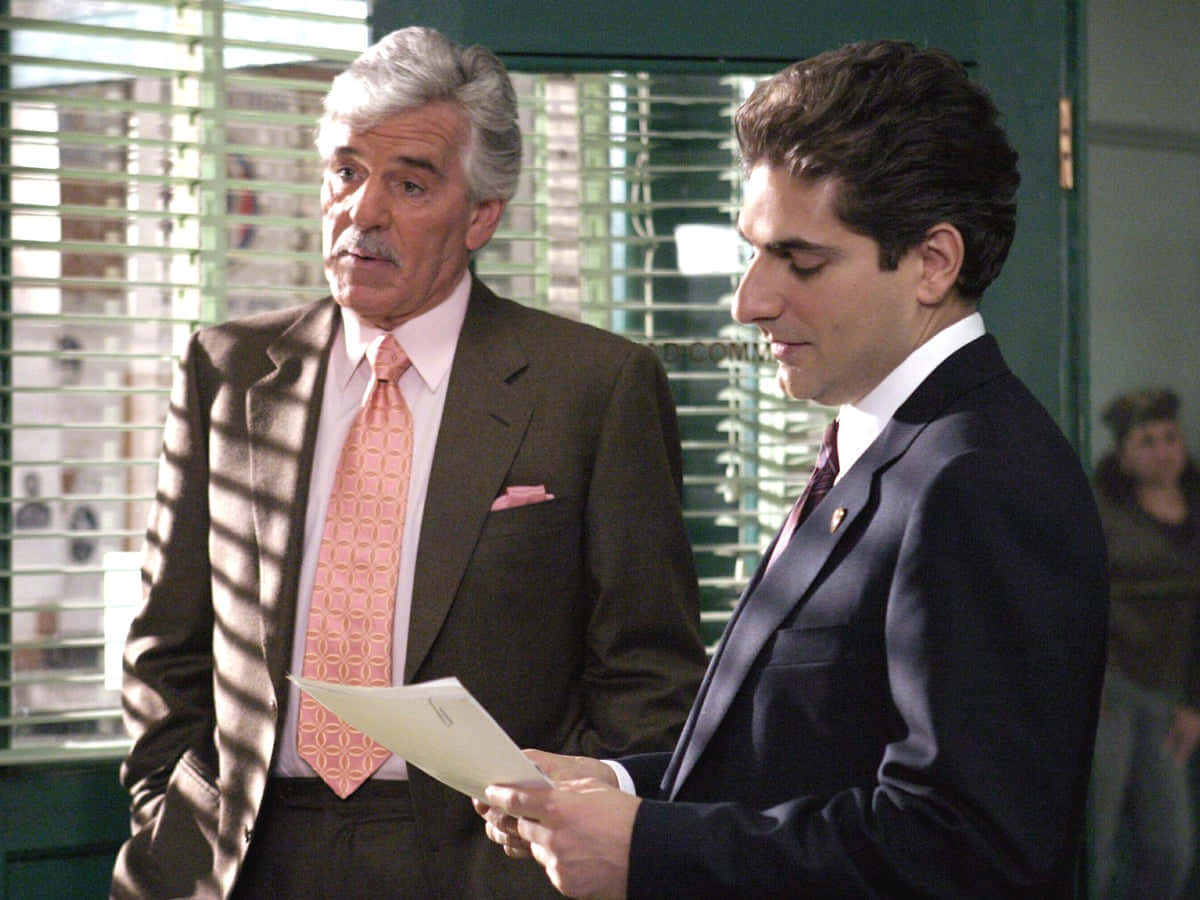 Dennis Farina Smiling In A Suit Background