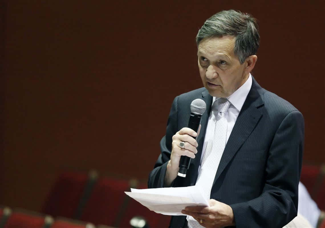 Dennis Kucinich Holding A Pen And Microphone Background