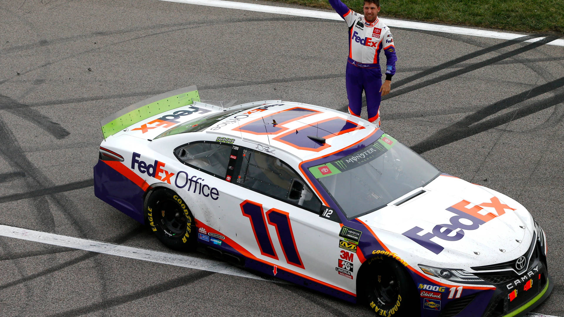 Denny Hamlin Poses Next To His Racing Car Background