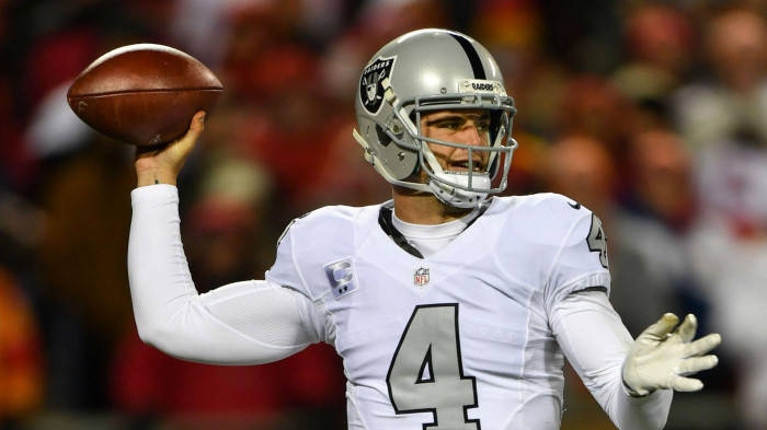 Derek Carr In White Taking Aim With Ball Background