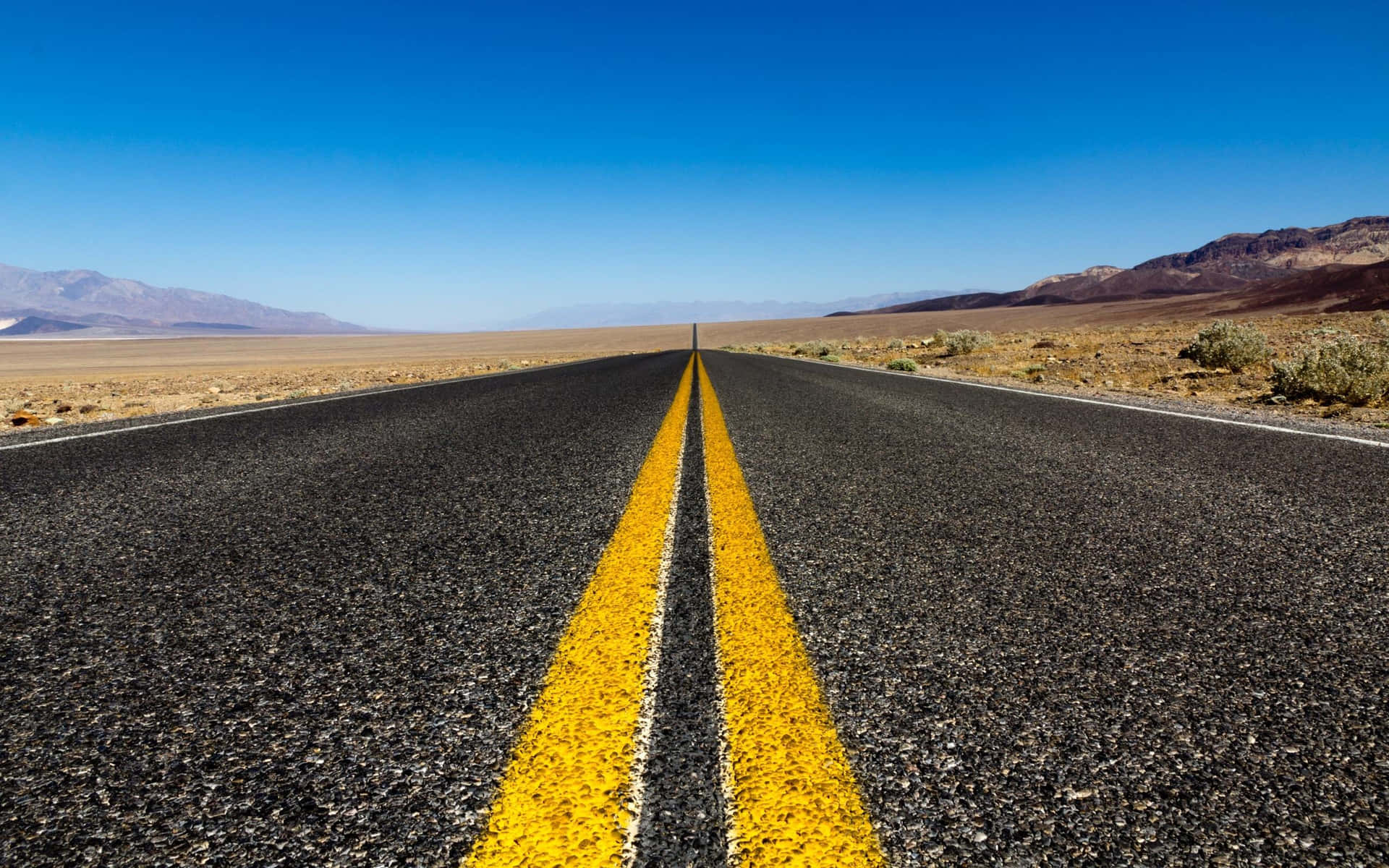 Desert_ Road_ Leading_to_ Mountains Background