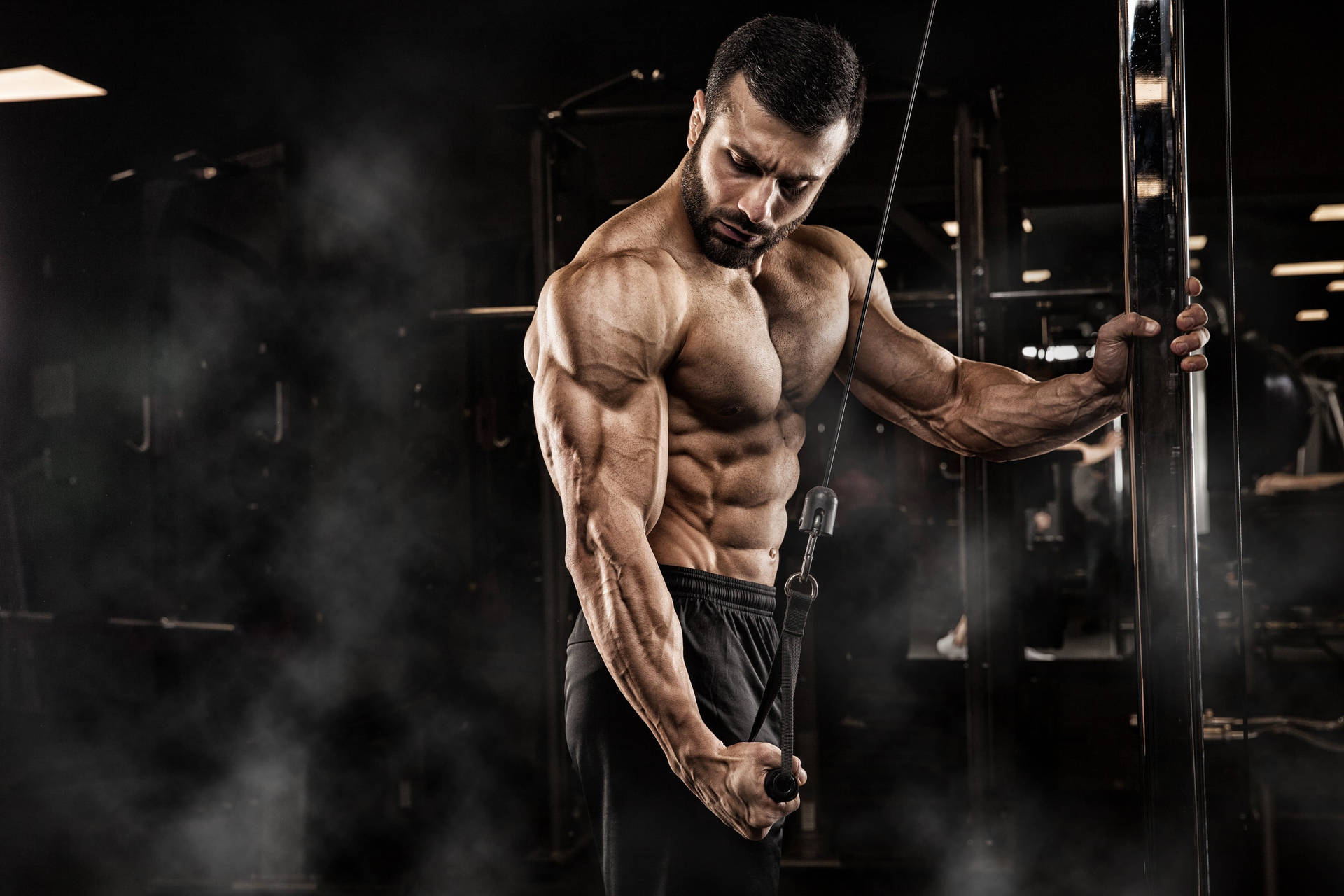 Determined Muscle Man Performing Single Arm Tricep Pushdown Background