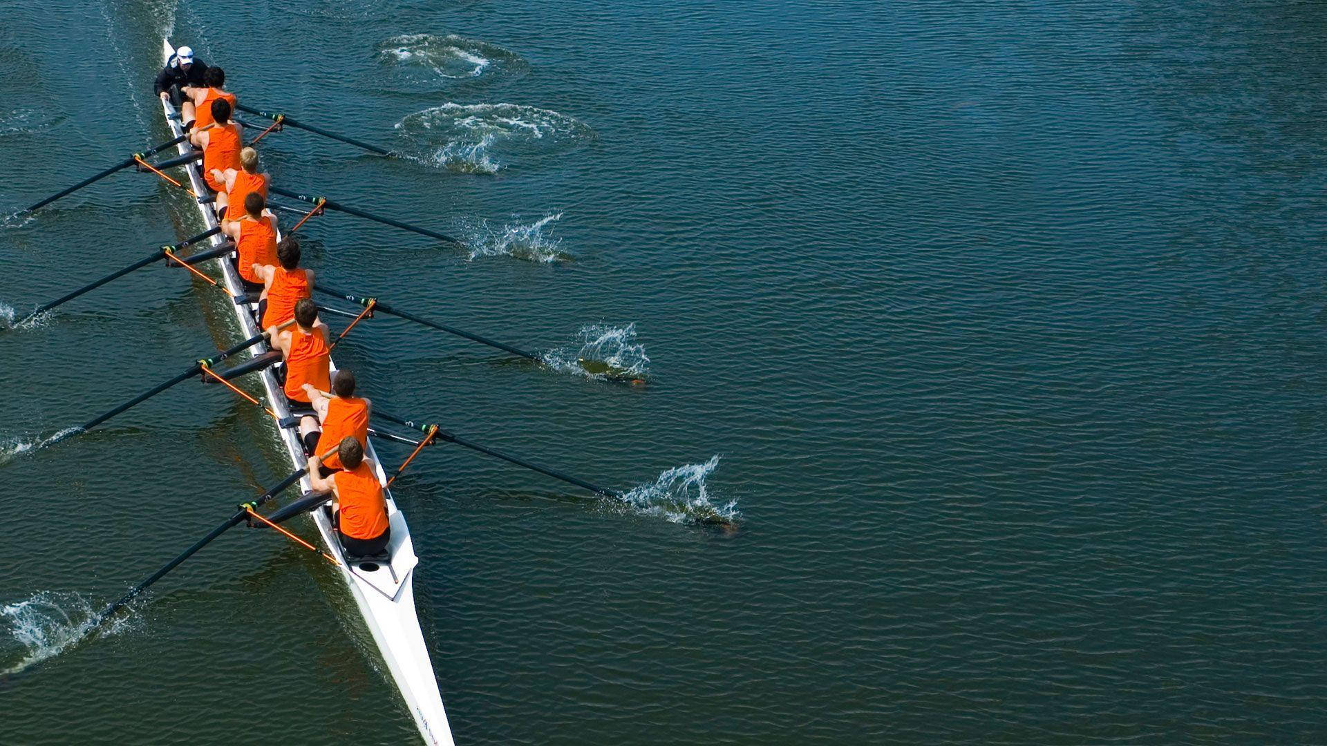Determined Rowing Team In Action Background