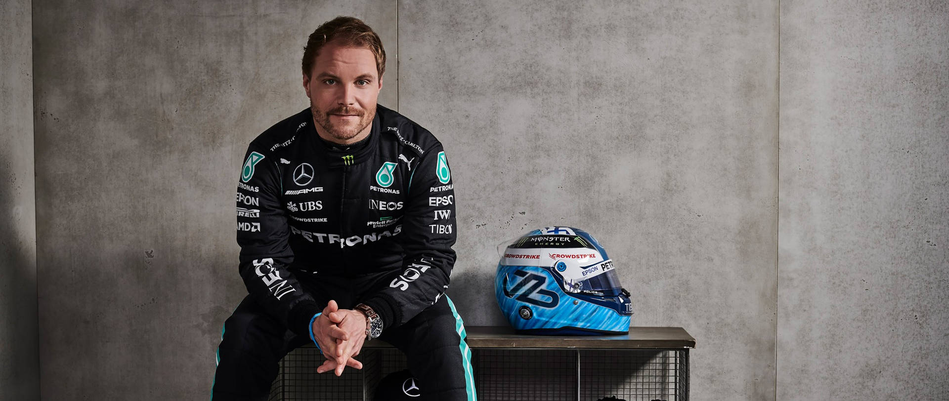 Determined Valtteri Bottas Sitting With His Racing Helmet Background