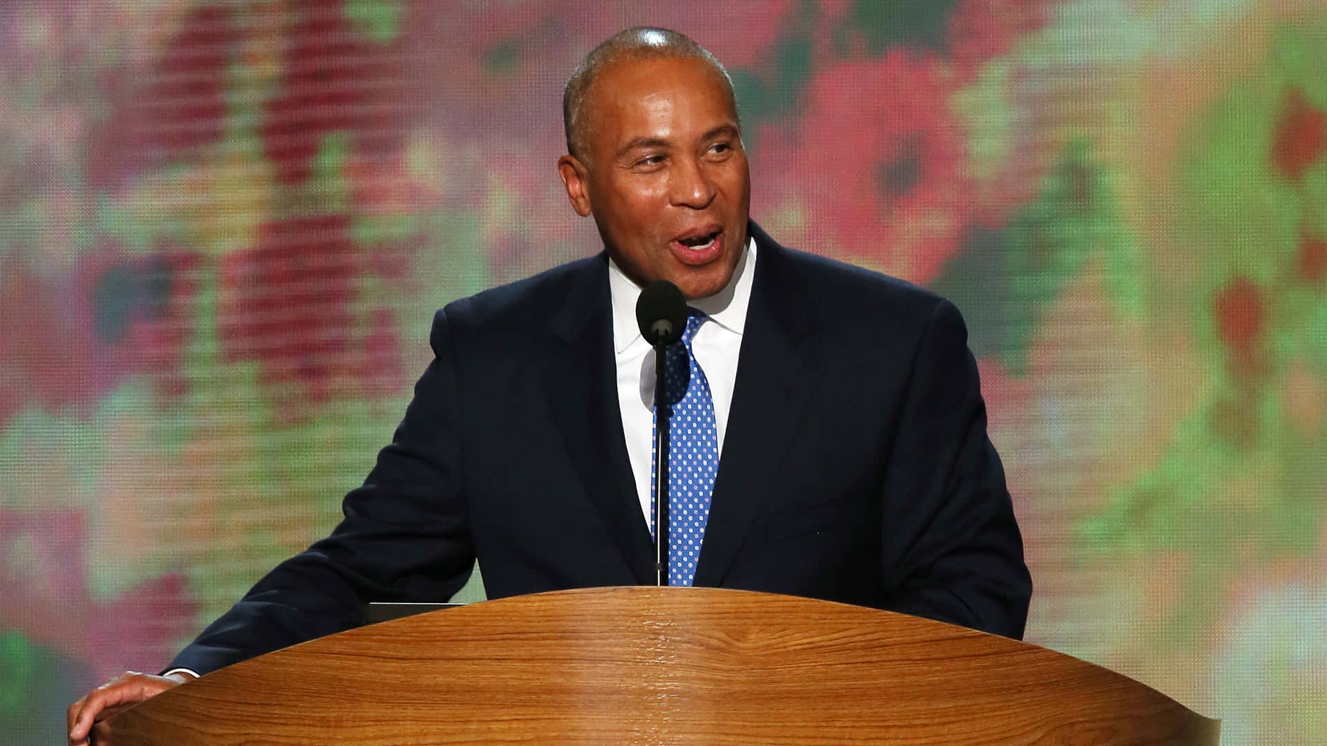 Deval Patrick Speaking Behind A Podium Background