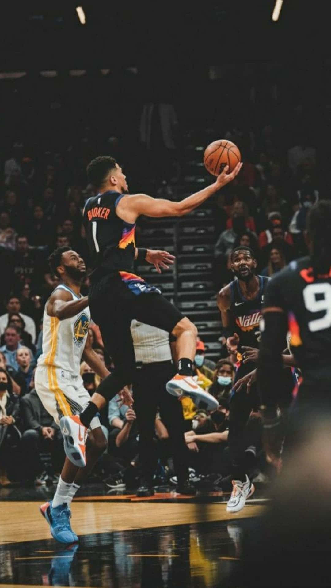 Devin Booker, Nba All-star And Phoenix Suns Guard, Exhibiting Strength Of His Team Mascot Background