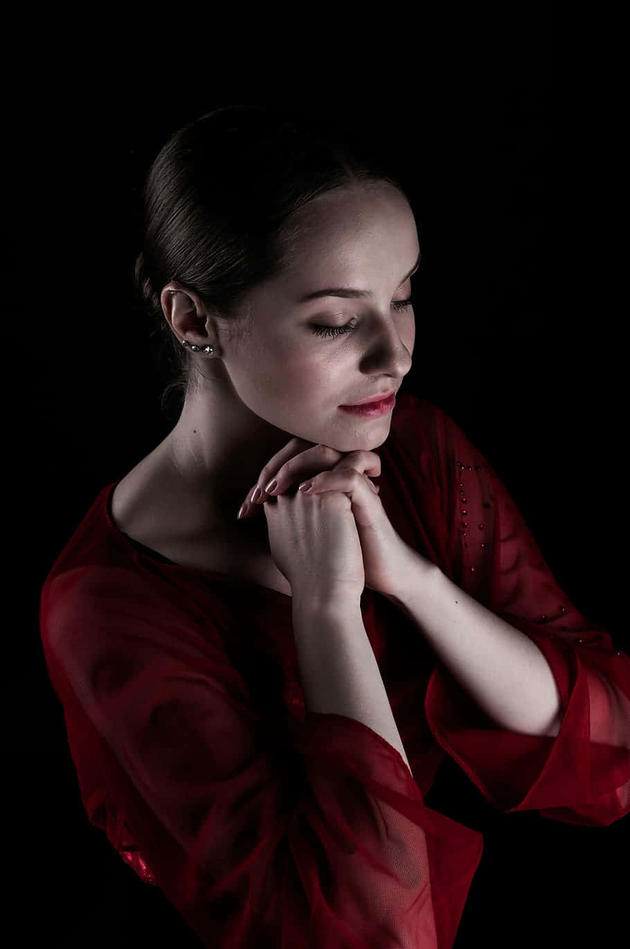 Devout Woman In Red Dress Engaging In Solitary Prayer Background