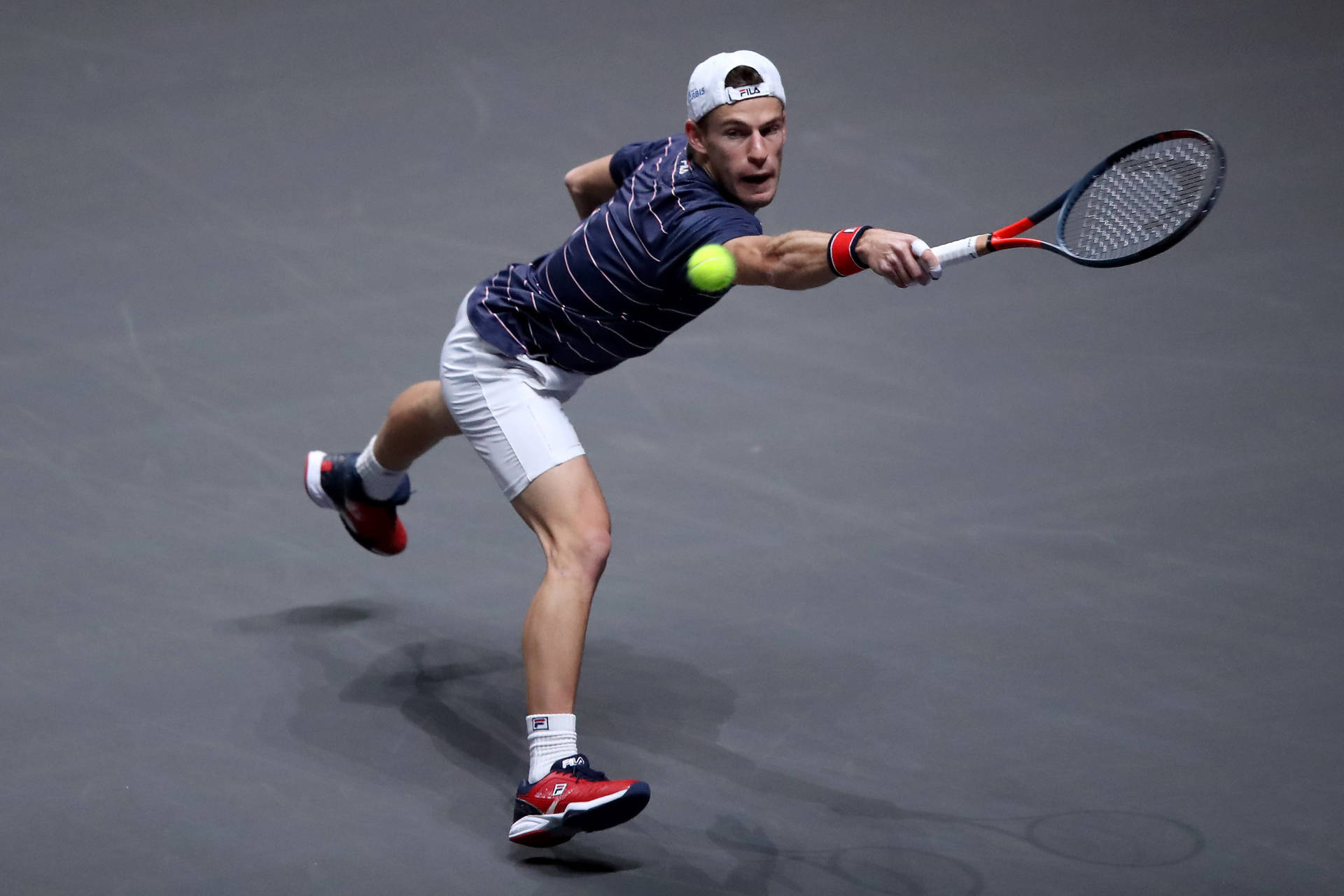 Diego Schwartzman Delivering A Powerful Leap Shot In A Tennis Match. Background