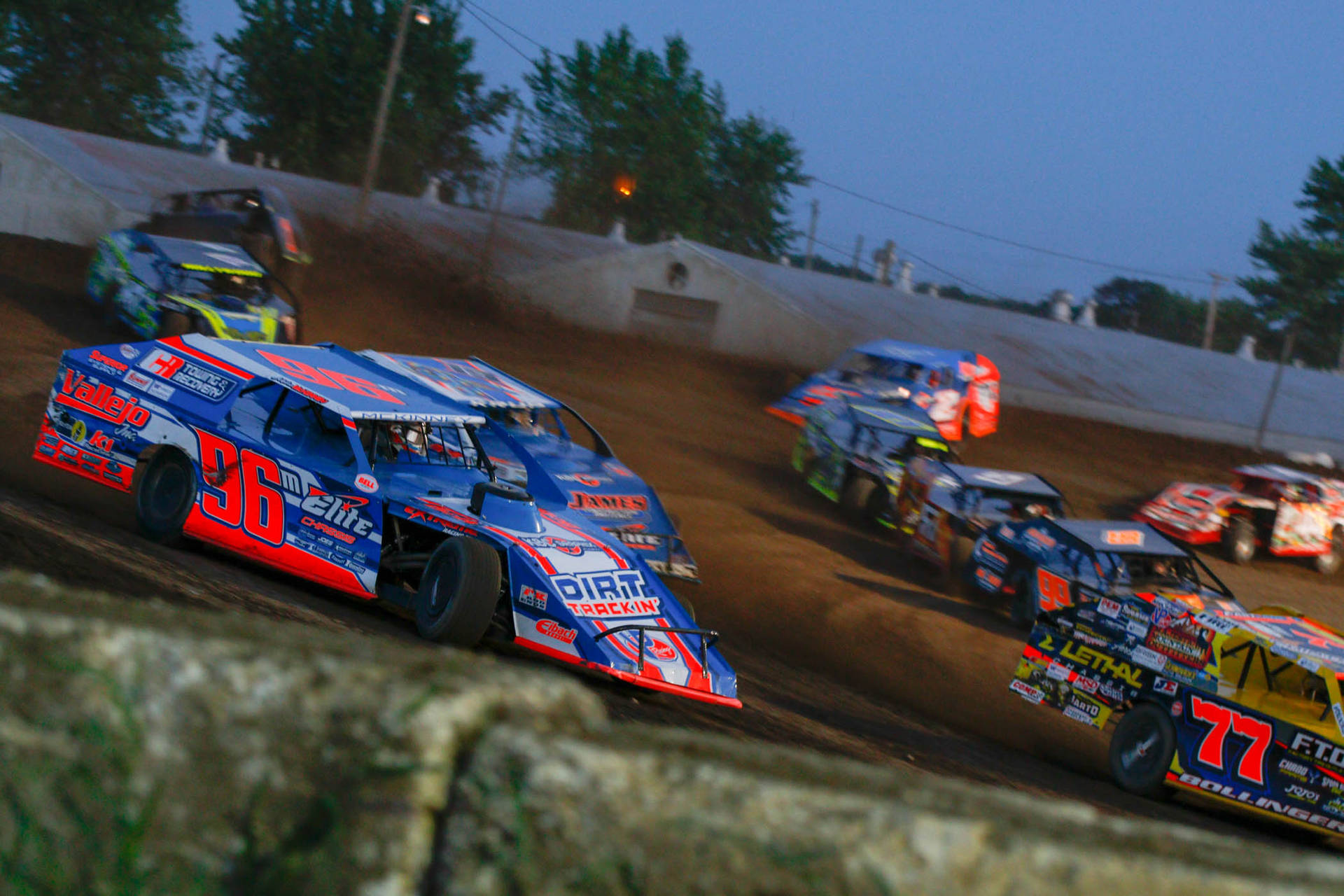 Dirt Cars Racing On A Dirt Track Background