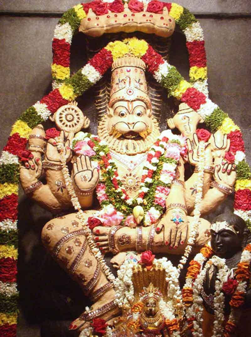 Divine Narasimha Statue Adorned With Vibrant Flowers Background