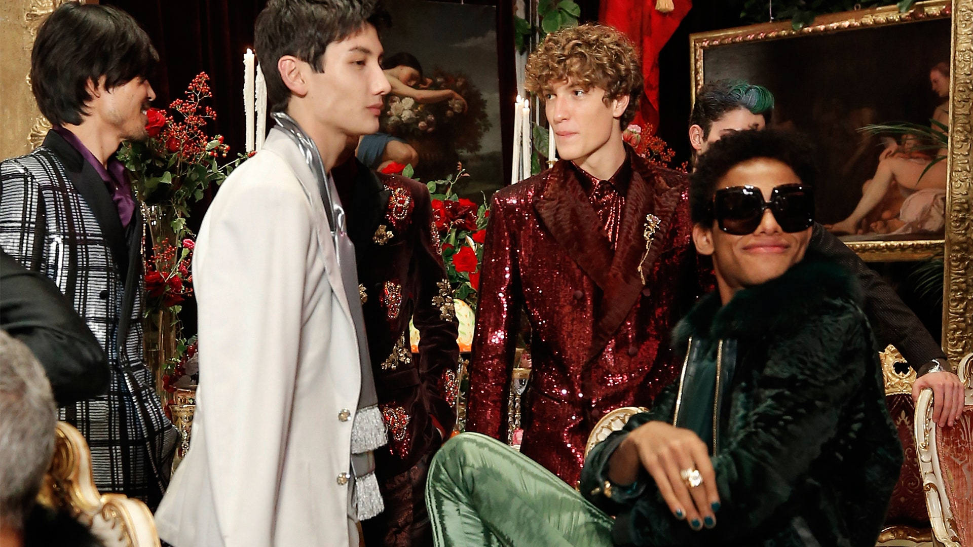 Dolce And Gabbana Models In Extravagant Clothing Sitting Around Background