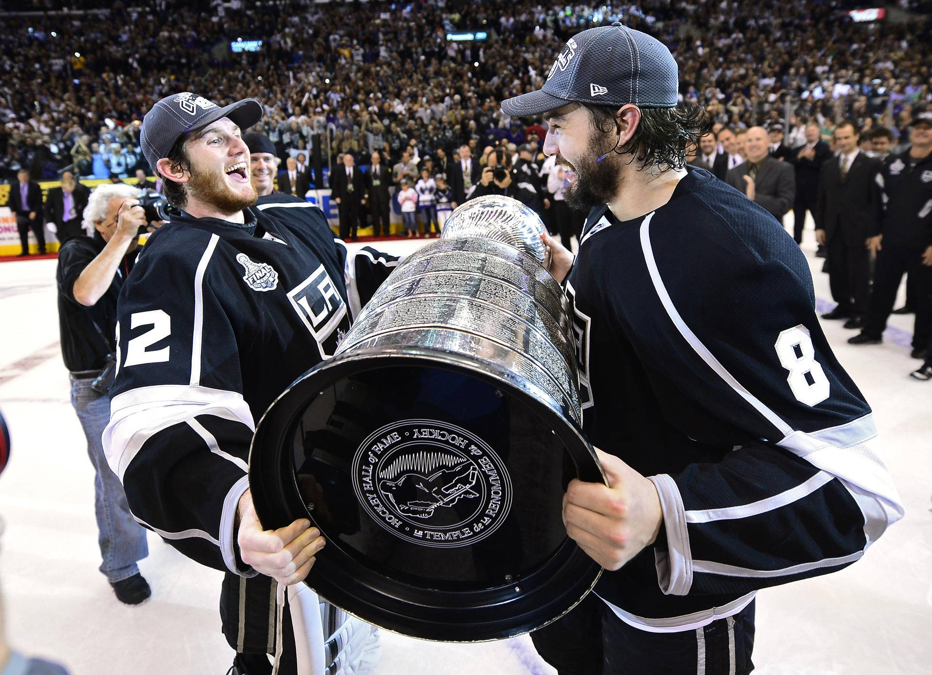 Drew Doughty Holding The Stanley Cup With Team Player Jonathan Quick Background