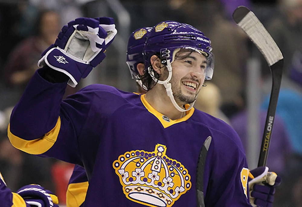 Drew Doughty Smiling While Wearing Vintage Jersey While Holding Hockey Stick Background