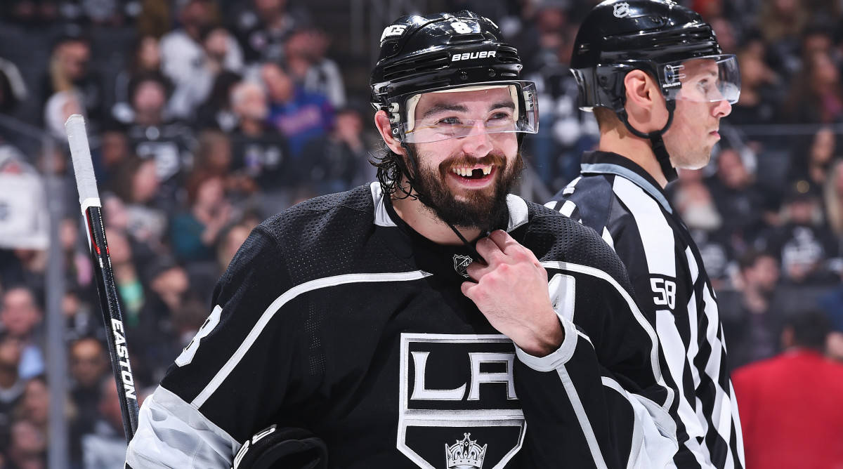 Drew Doughty Smiling With Missing Teeth While Holding Helmet Strap Background