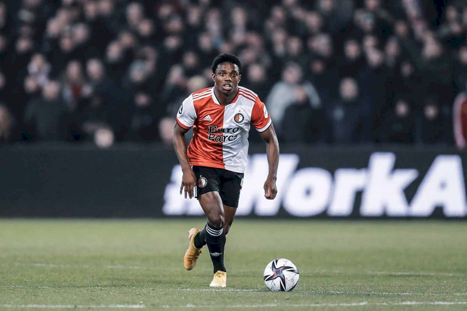 Dynamic Athlete Tyrell Malacia In Orange And White Uniform Background