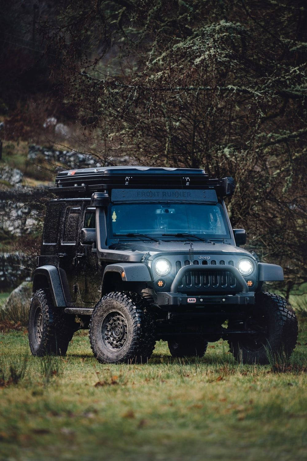 Dynamic Black Jeep Wrangler With Top Rack Over Rugged Terrain