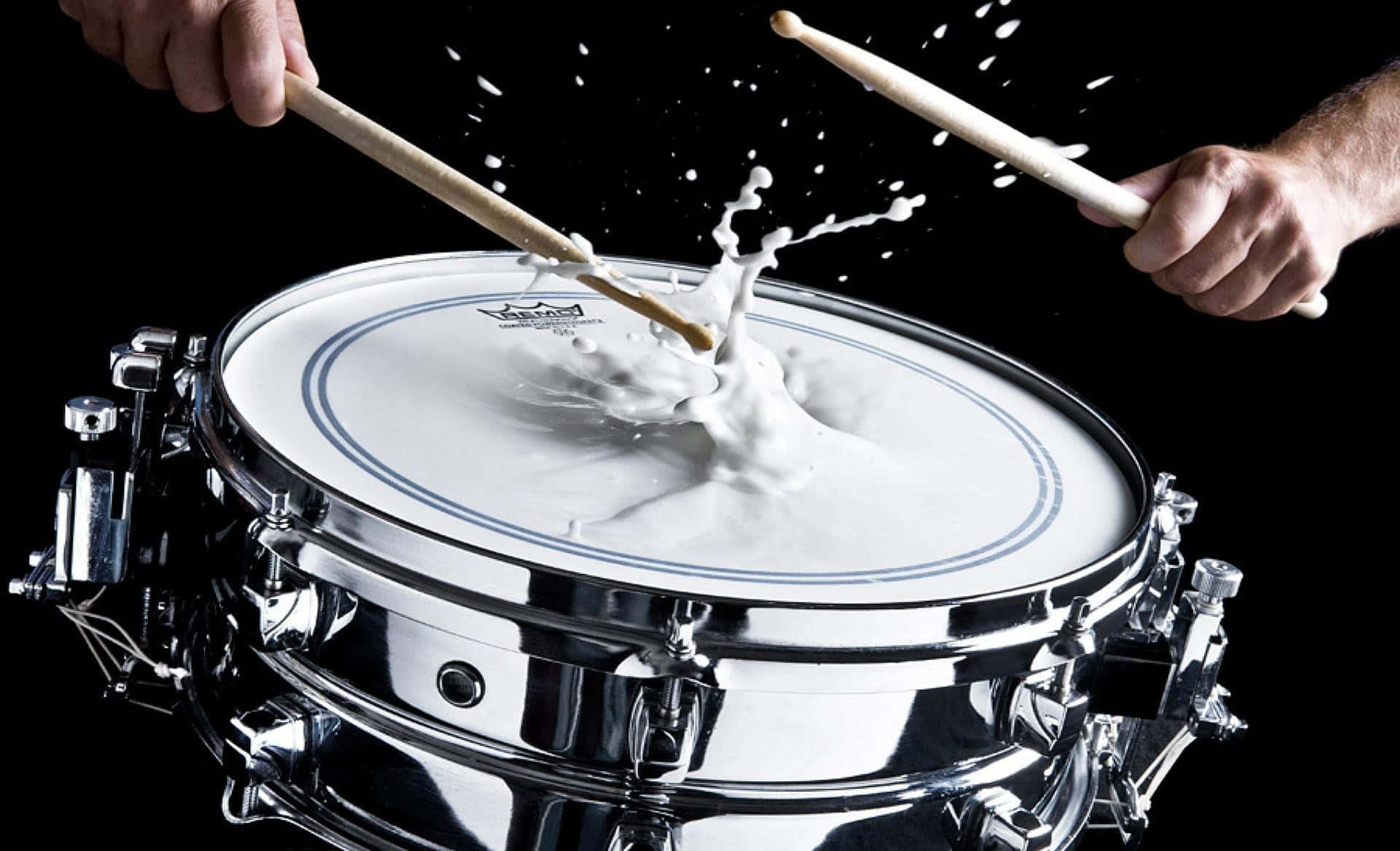 Dynamic Drumstick Impacton Snarewith Splash Background