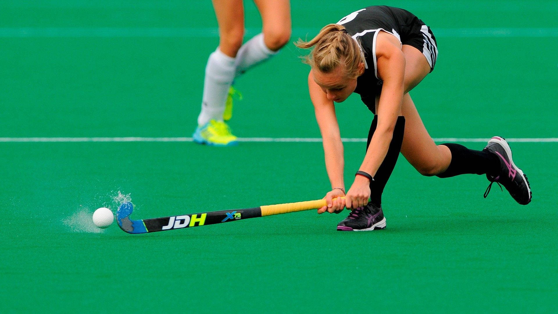 Dynamic Female Field Hockey Player In Action Background