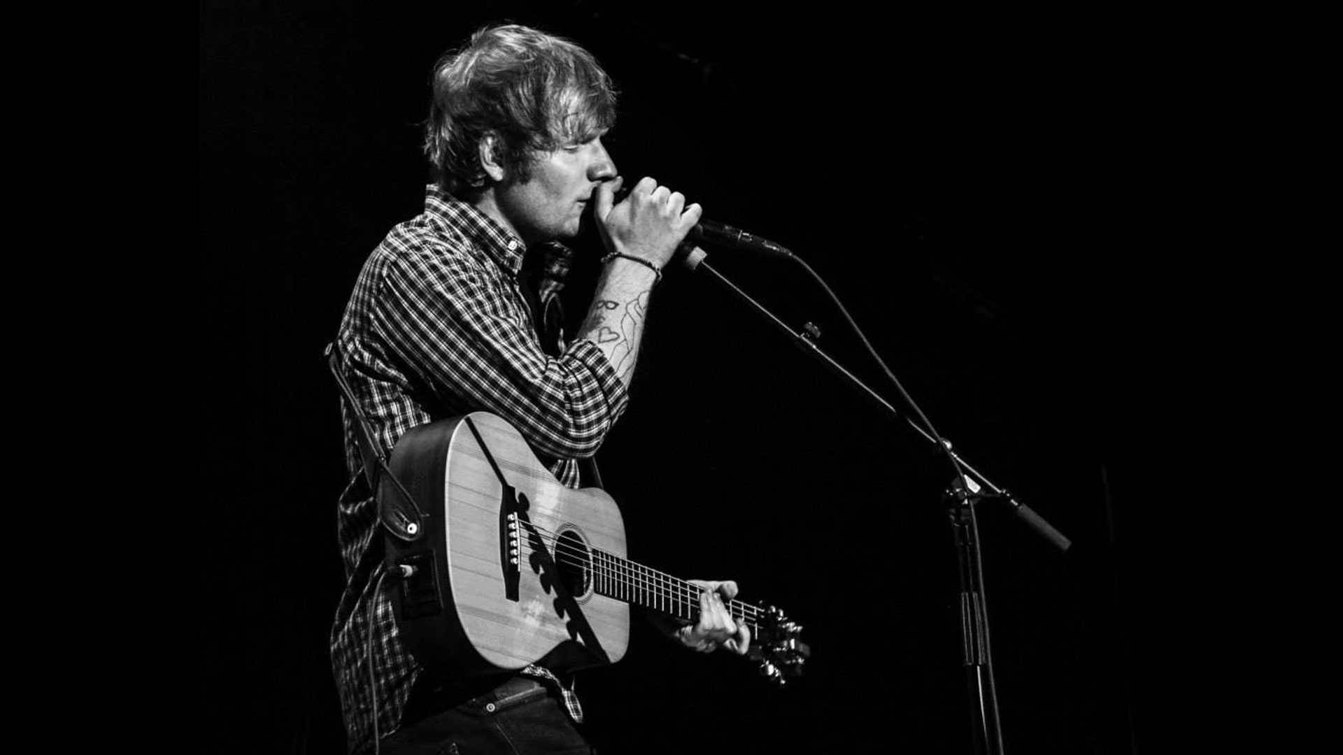 Ed Sheeran Strumming Away In Front Of A Live Audience Background