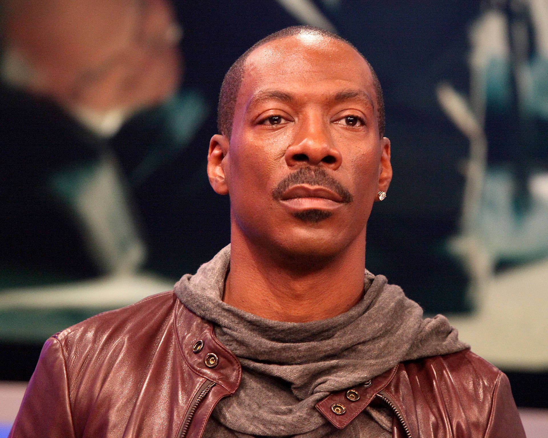 Eddie Murphy Looking Suave In A Brown Leather Jacket Background