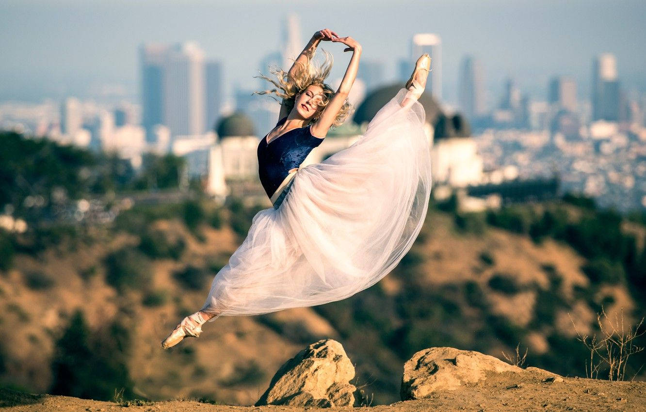 Effortless Elegance: A Ballet Dancer In Mid-air Split Pose Background