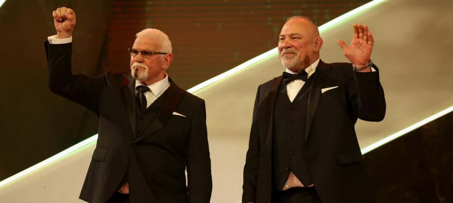 Elegant Eventwith Two Gentlemen Raising Hands Background